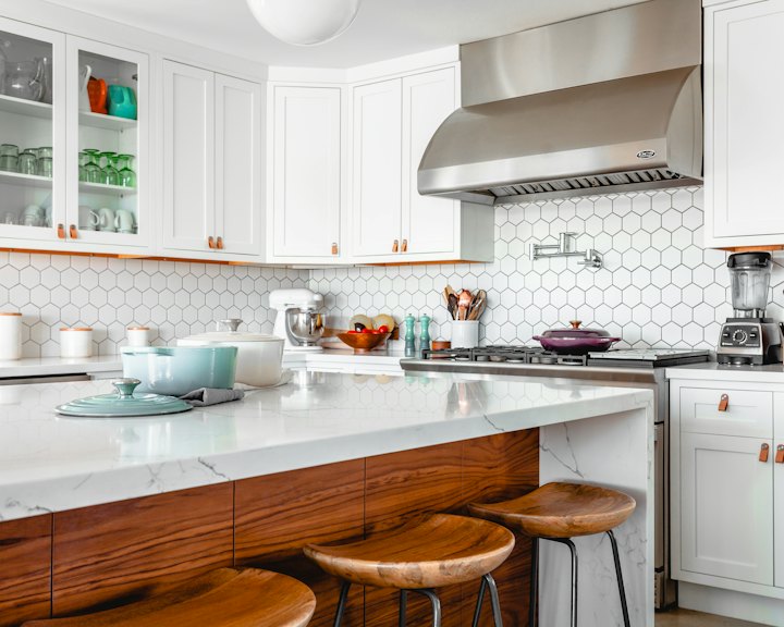 A bright, spotless white kitchen with an island and stools