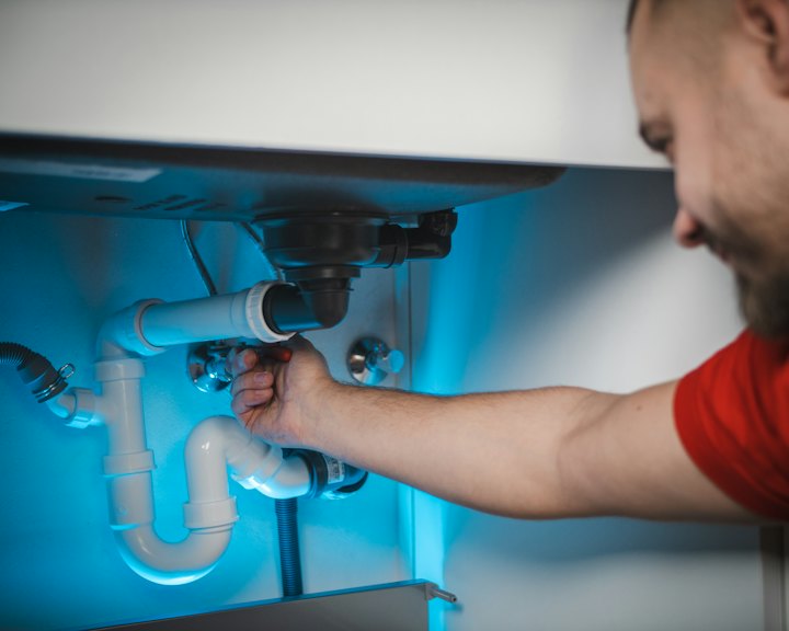 A plumber fixing pipes under a sink