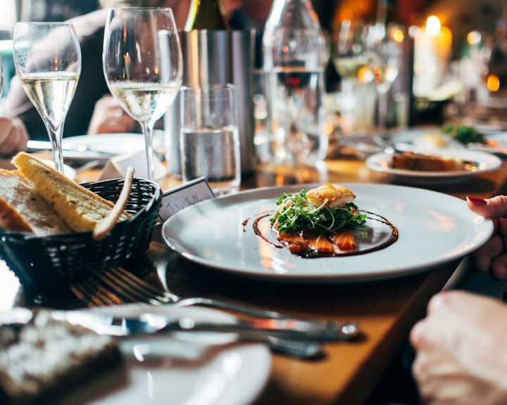 A plated dinner on a candlelit restaurant table with wine glasses